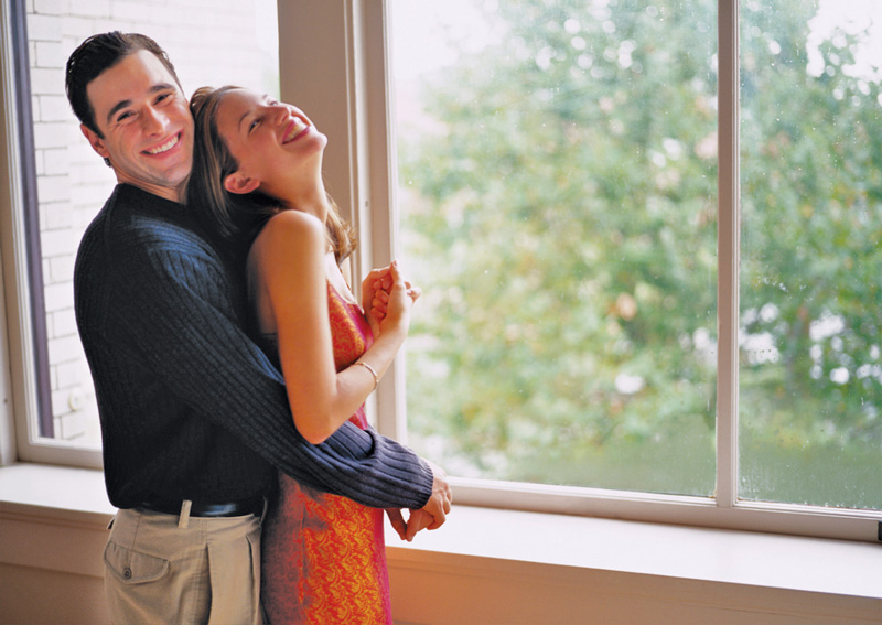Happy couple embraced in front of window